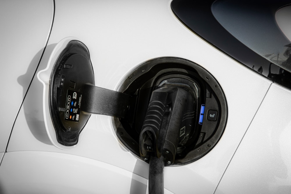 Κοντινό στο σημείο φόρτισης λευκού Ford Puma Gen-E Van με συνδεδεμένο καλώδιο φόρτισης.