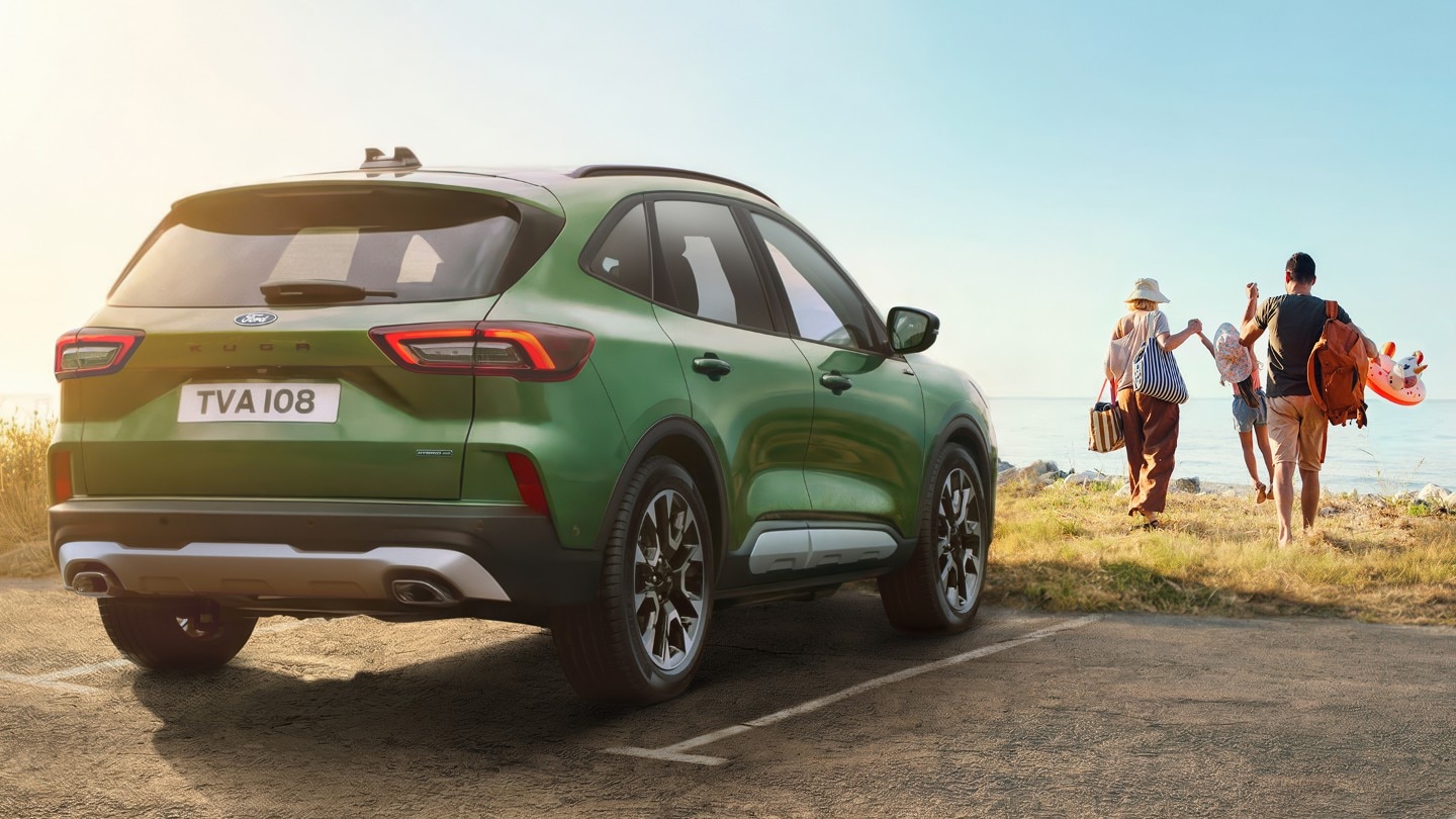 Πράσινο SUV παρκαρισμένο δίπλα σε παραλία με οικογένεια.