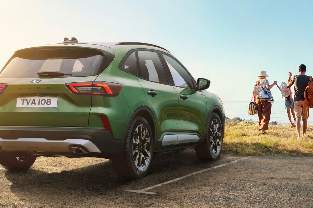 Πράσινο SUV παρκαρισμένο δίπλα σε παραλία με οικογένεια.