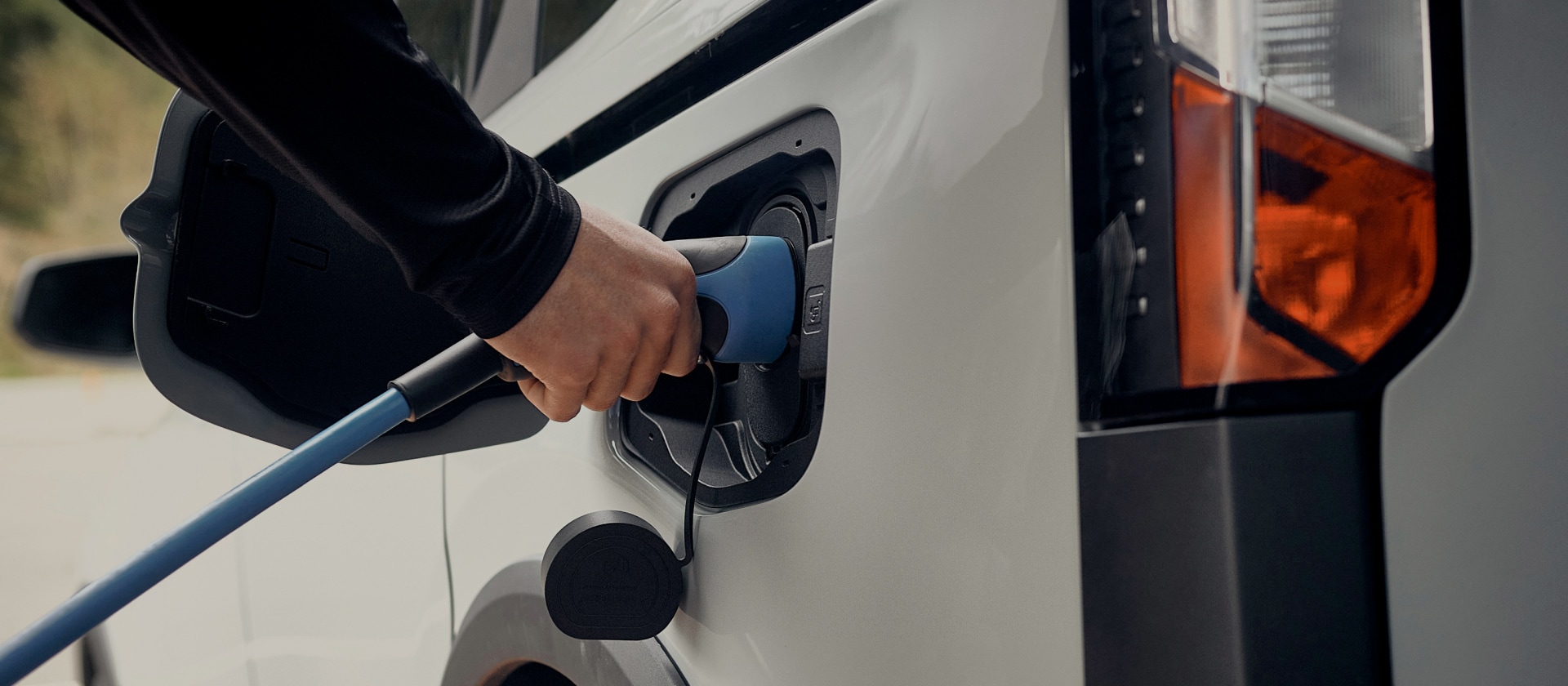 Κοντινή λήψη ενός λευκού ηλεκτρικού Ford που συνδέεται σε φορτιστή EV.