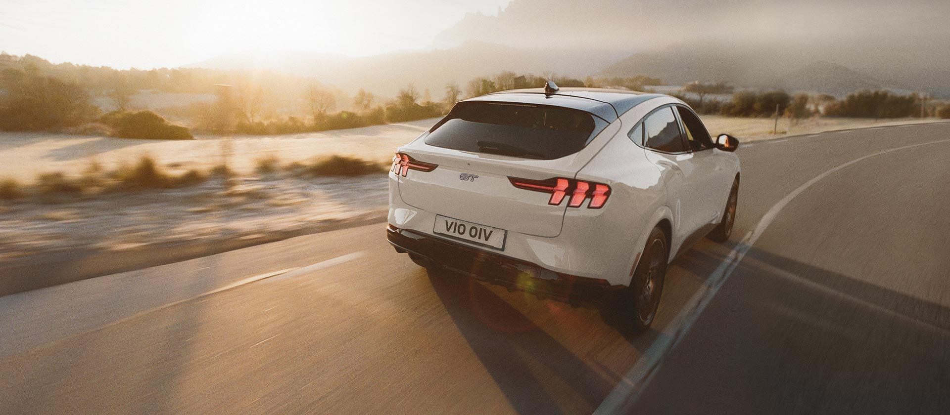 Ένα ασημί ηλεκτρικό Ford Mustang Mach-E οδηγείται σε έναν ανοιχτό, μεγάλο δρόμο.