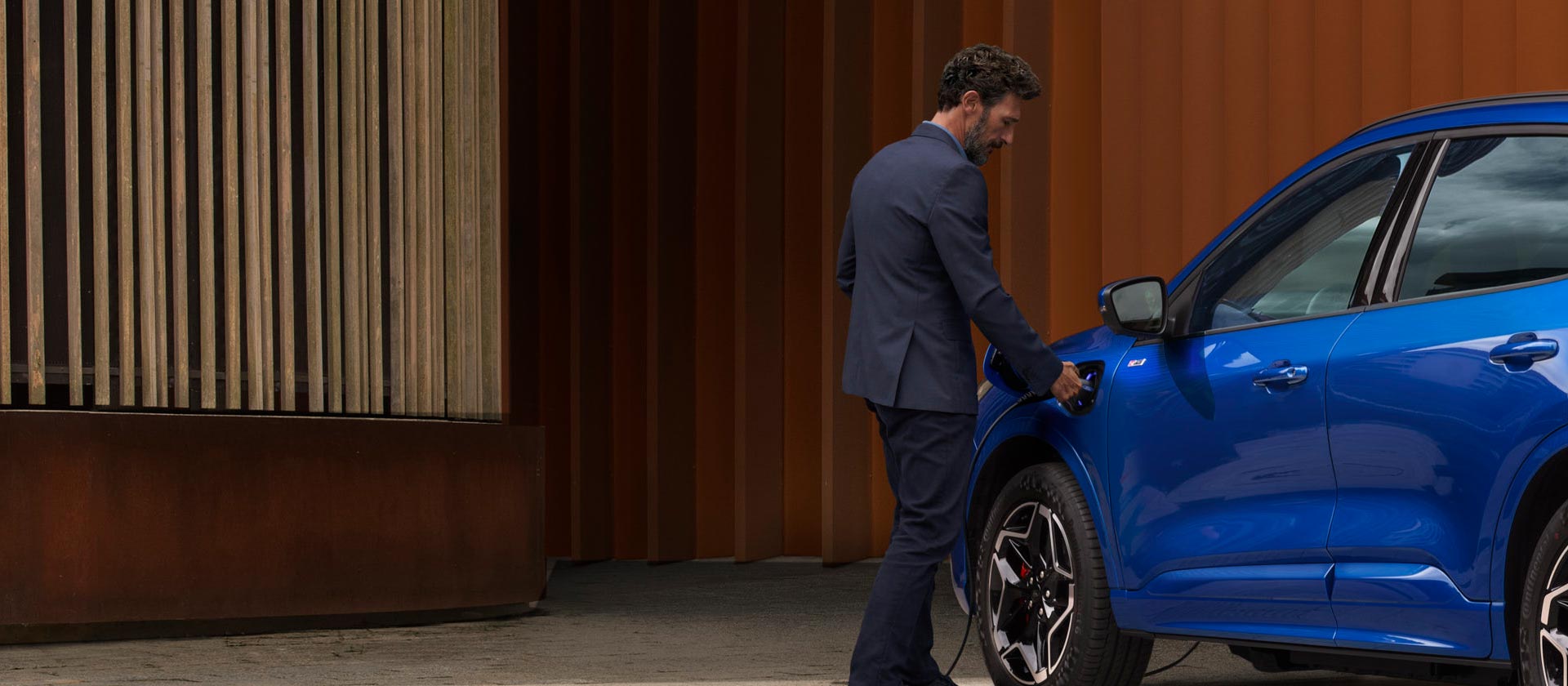 Ένα άτομο συνδέει ένα plug-in υβριδικό Ford σε καλώδιο οικιακής φόρτισης.