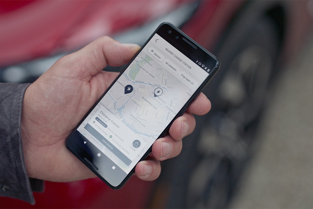 Ένα smartphone που εμφανίζει την εφαρμογή FordPass™ με κοντινούς σταθμούς φόρτισης για δημόσια φόρτιση EV.