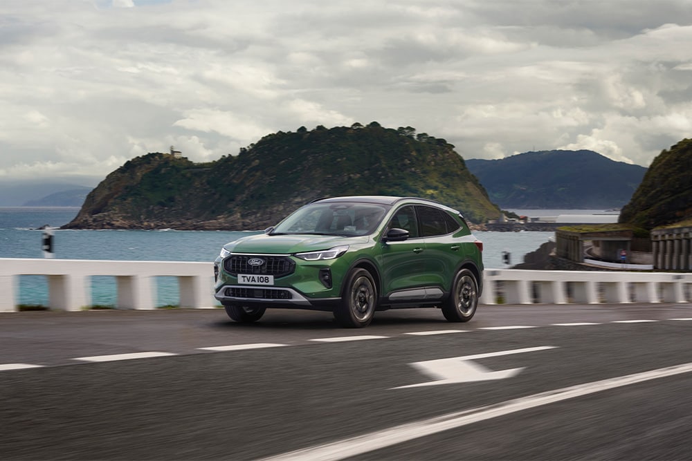 Ένα πράσινο αυτοφορτιζόμενο υβριδικό Ford Kuga οδηγείται σε μια γραφική διαδρομή.