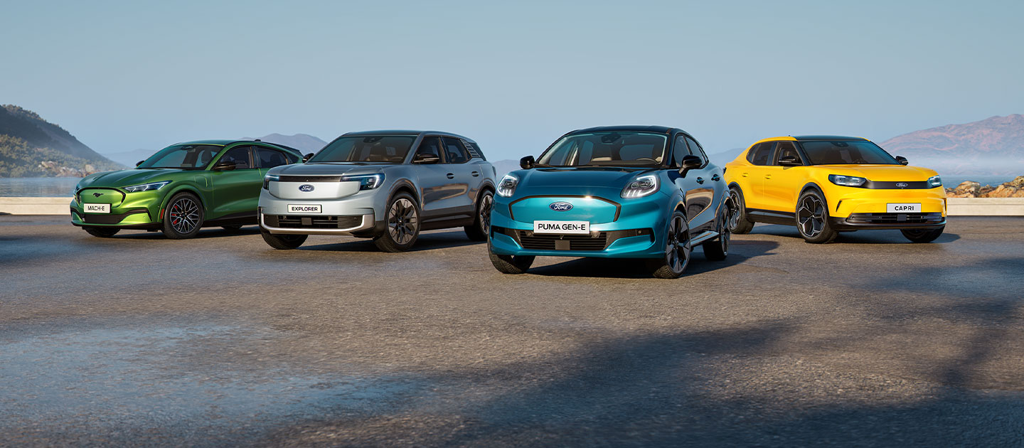 Μια συλλογή από διαφορετικά ηλεκτρικά αυτοκίνητα Ford σταθμευμένα σε ένα δύσβατο παραλιακό τοπίο.