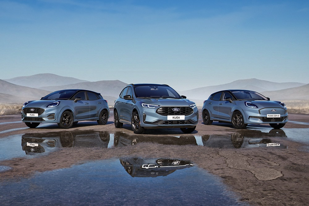 Ένα Ford Puma, ένα Ford Kuga και ένα Ford Puma Gen-E σταθμευμένα σε έναν βρεγμένο δρόμο με βουνά στο φόντο.