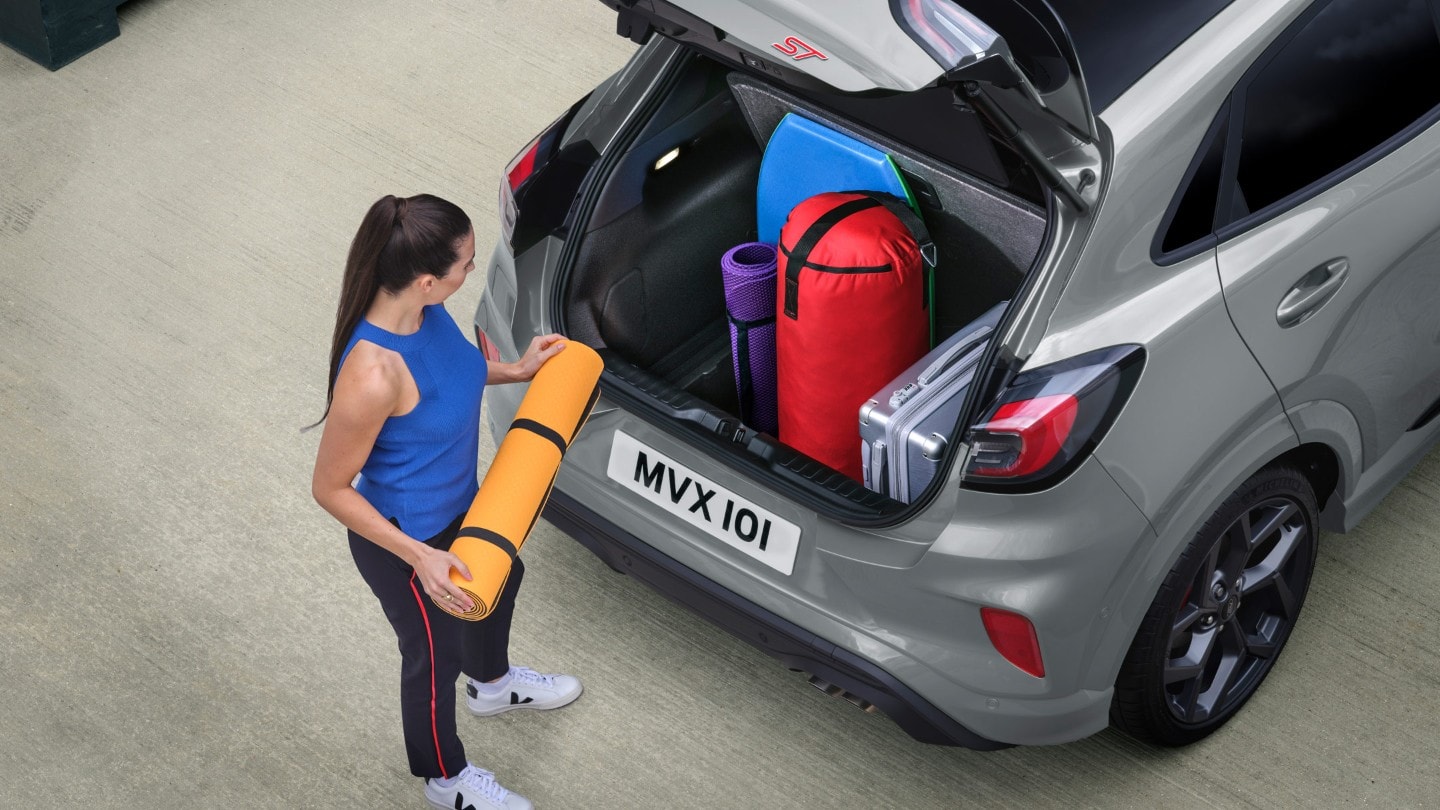 Person loading baggage into the storage compartment of a Ford Puma ST