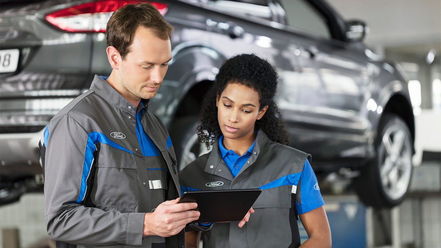 Δύο ειδικοί επισκευών Ford ελέγχουν το online σύστημα κρατήσεων service από κινητό.