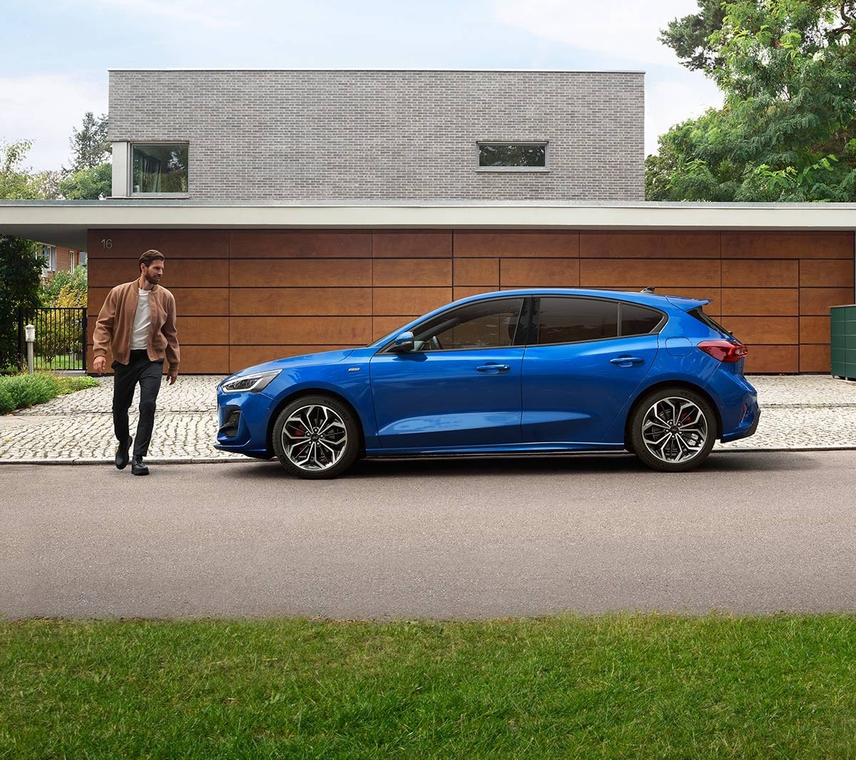 Man approaching a blue Ford Focus parked in front of a house