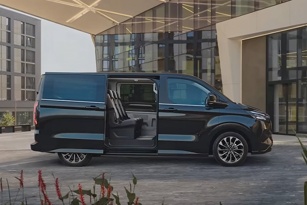 Μαύρο Ford E-Tourneo Custom σταθμευμένο με την πλευρική πόρτα ανοιχτή, από όπου φαίνονται τα εσωτερικά καθίσματα.
