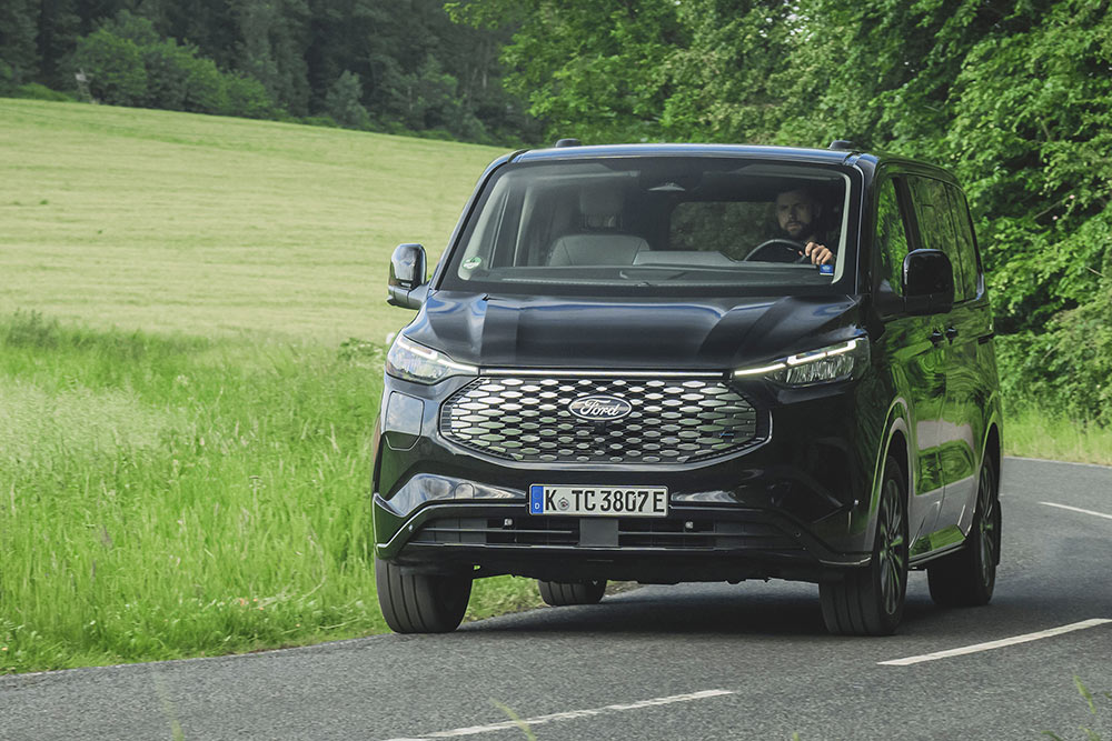 Μαύρο Ford E-Tourneo Custom που κινείται σε επαρχιακό δρόμο.