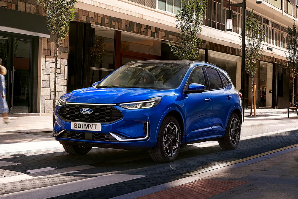 A Ford Kuga ST Line car in the colour Desert Island Blue shown parked in a residential area. 