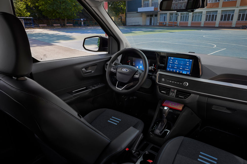 Το εσωτερικό ενός Ford Tourneo Courier, που δείχνει το ταμπλό, το τιμόνι, την οθόνη ψυχαγωγίας και το κάθισμα του συνοδηγού.