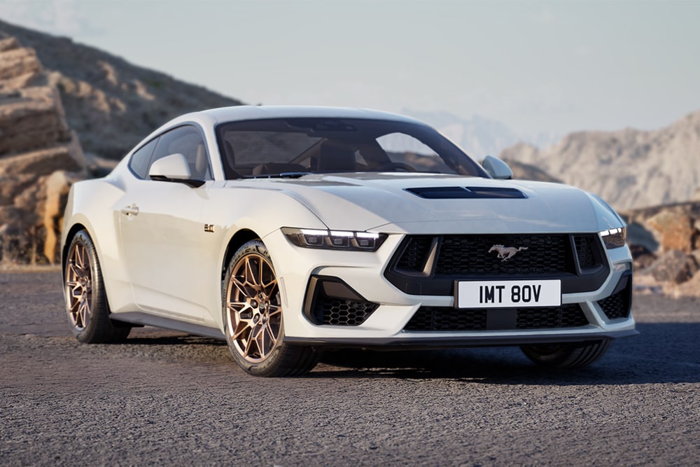 A Ford Mustang GT Fastback with Bronze Pack in Oxford White paint parked on a mountain road.