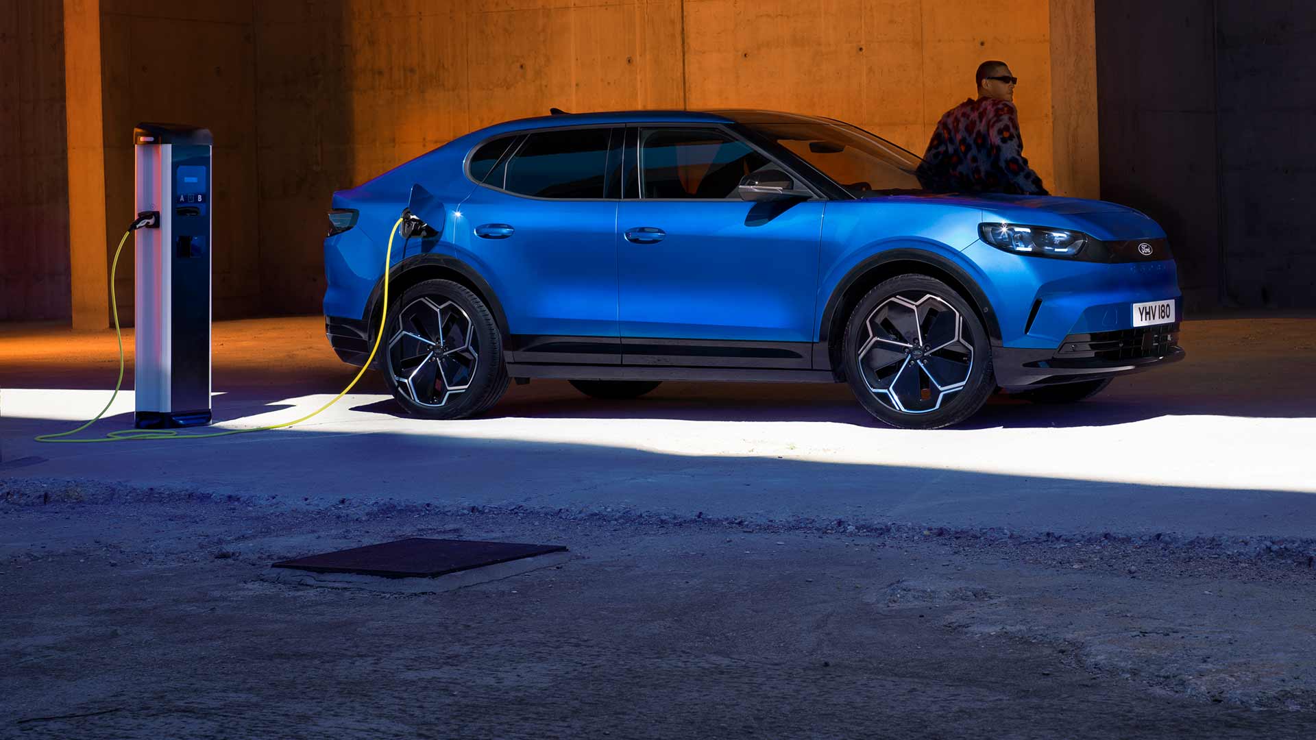 Ένα μπλε ηλεκτρικό Ford Capri®, συνδεδεμένο σε δημόσιο σημείο φόρτισης ηλεκτρικών οχημάτων.