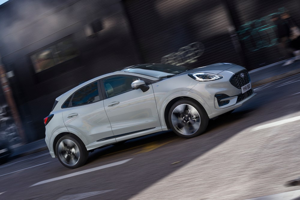 Ασημί Ford Puma της σειράς μικρών αυτοκινήτων της Ford που κινείται σε δρόμο μιας πόλης.