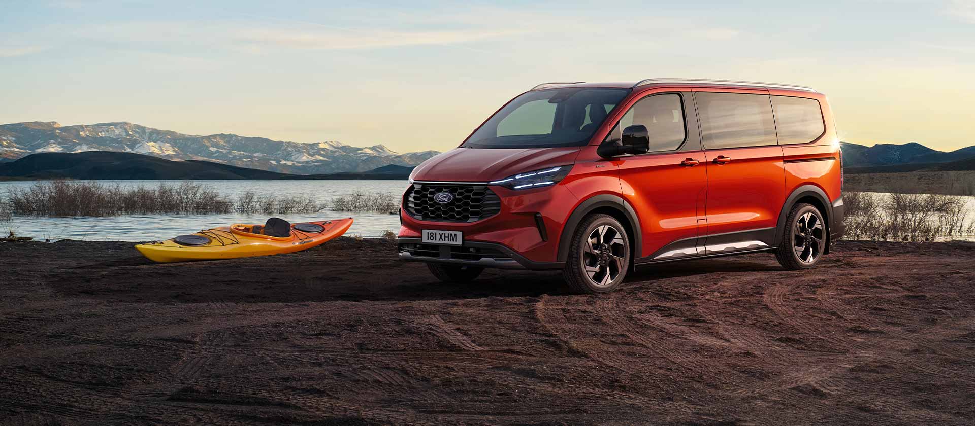 Κόκκινο Ford Tourneo Custom van σταθμευμένο κοντά σε μια λίμνη με ένα καγιάκ.
