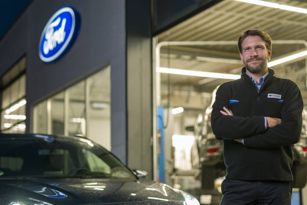 Τεχνικός Ford μπροστά από το συνεργείο και ένα γκρι όχημα