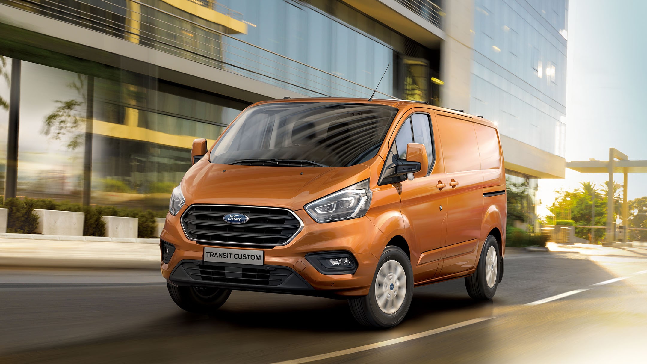 New Ford Transit Custom driving next to glass building