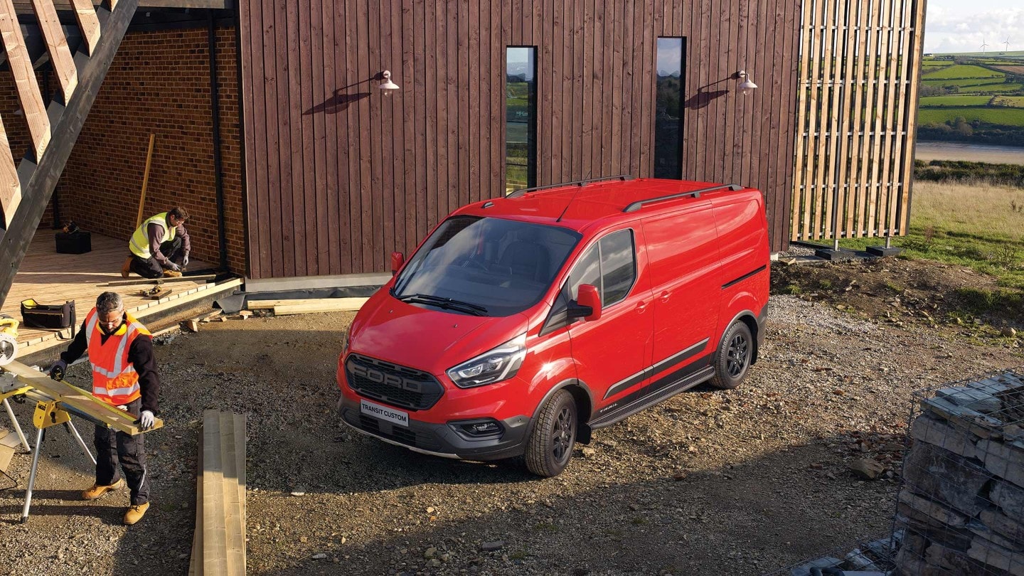 Ford Transit Custom shown from rear parking next to stone building with trees
