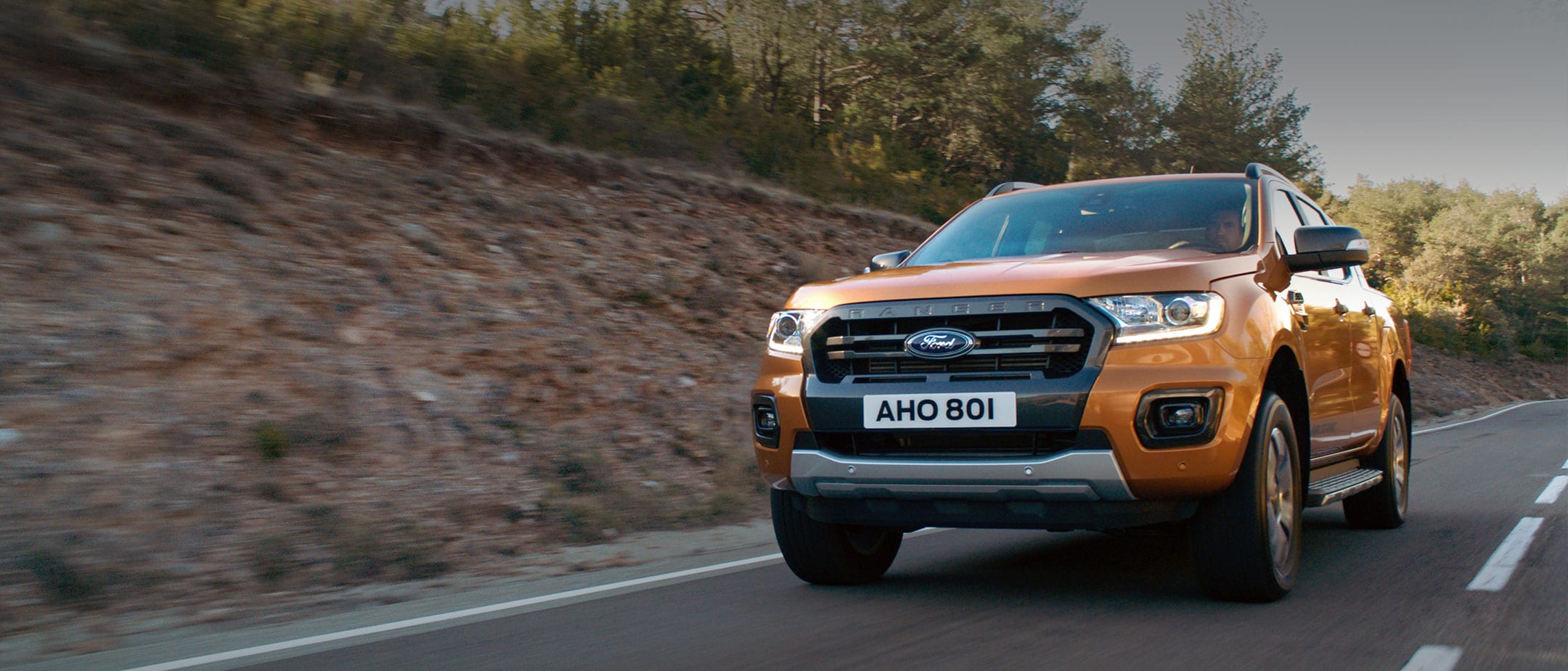 Οδήγηση Πορτοκαλί Ford Ranger Wildtrak στο δάσος, μπροστινή άποψη τριών τετάρτων Οδήγηση Πορτοκαλί Ford Ranger Wildtrak στο δάσος, μπροστινή άποψη τριών τετάρτων