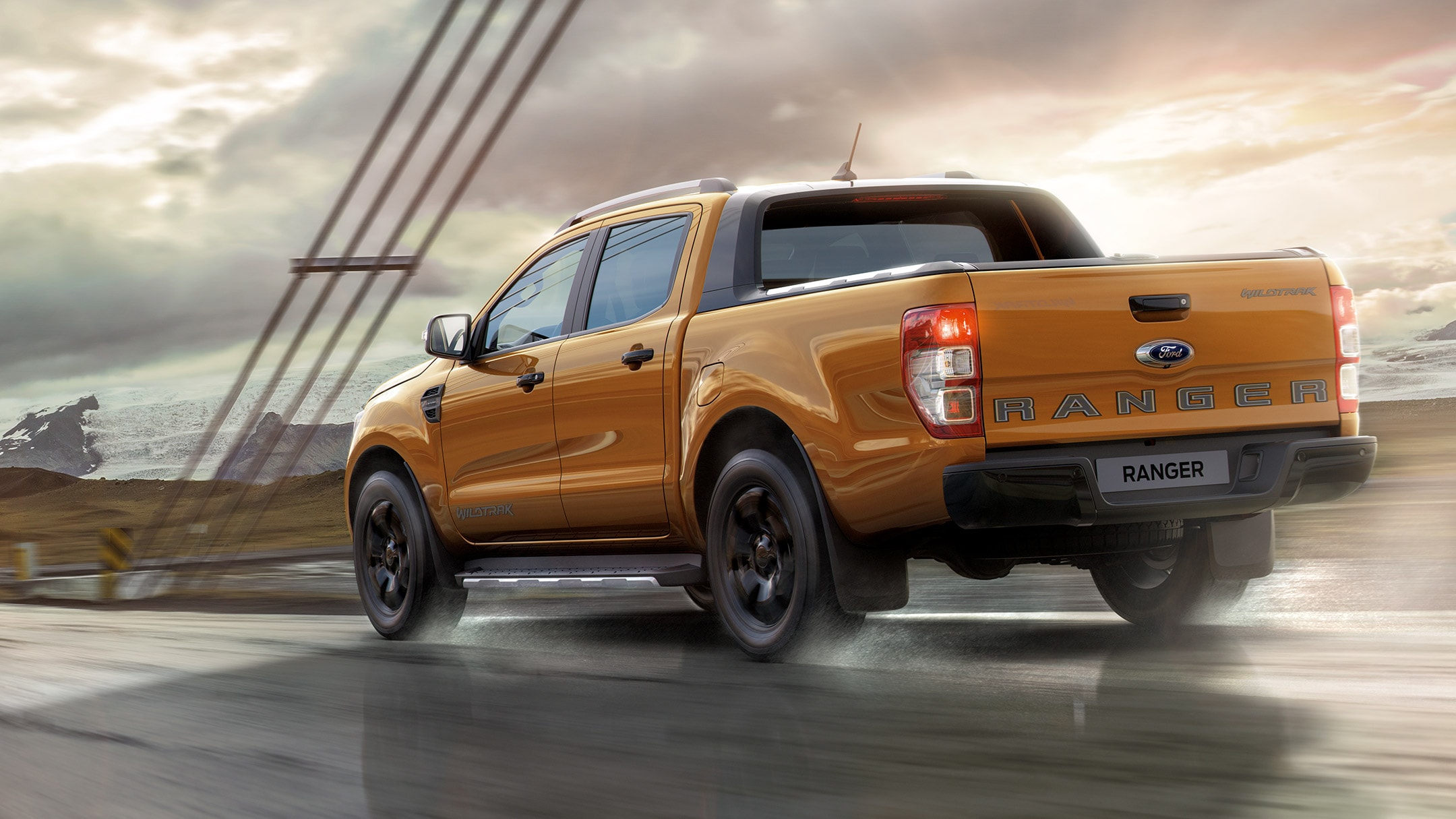 Οδήγηση Πορτοκαλί Ford Ranger Wildtrak στον αυτοκινητόδρομο, οπίσθια άποψη επτά όγδοων