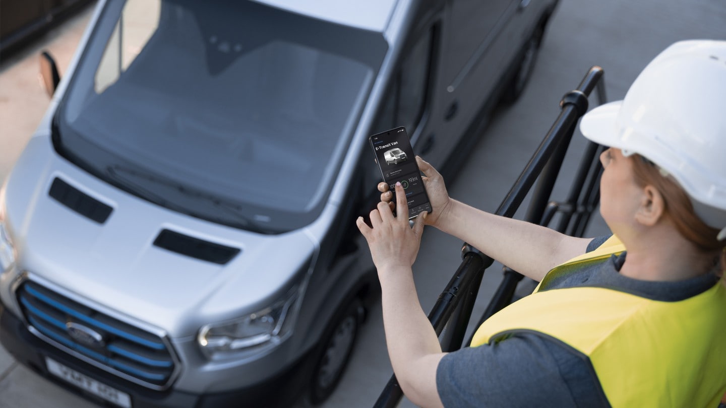 Person in high viz jacket checking mobile phone with Ford Transit in background