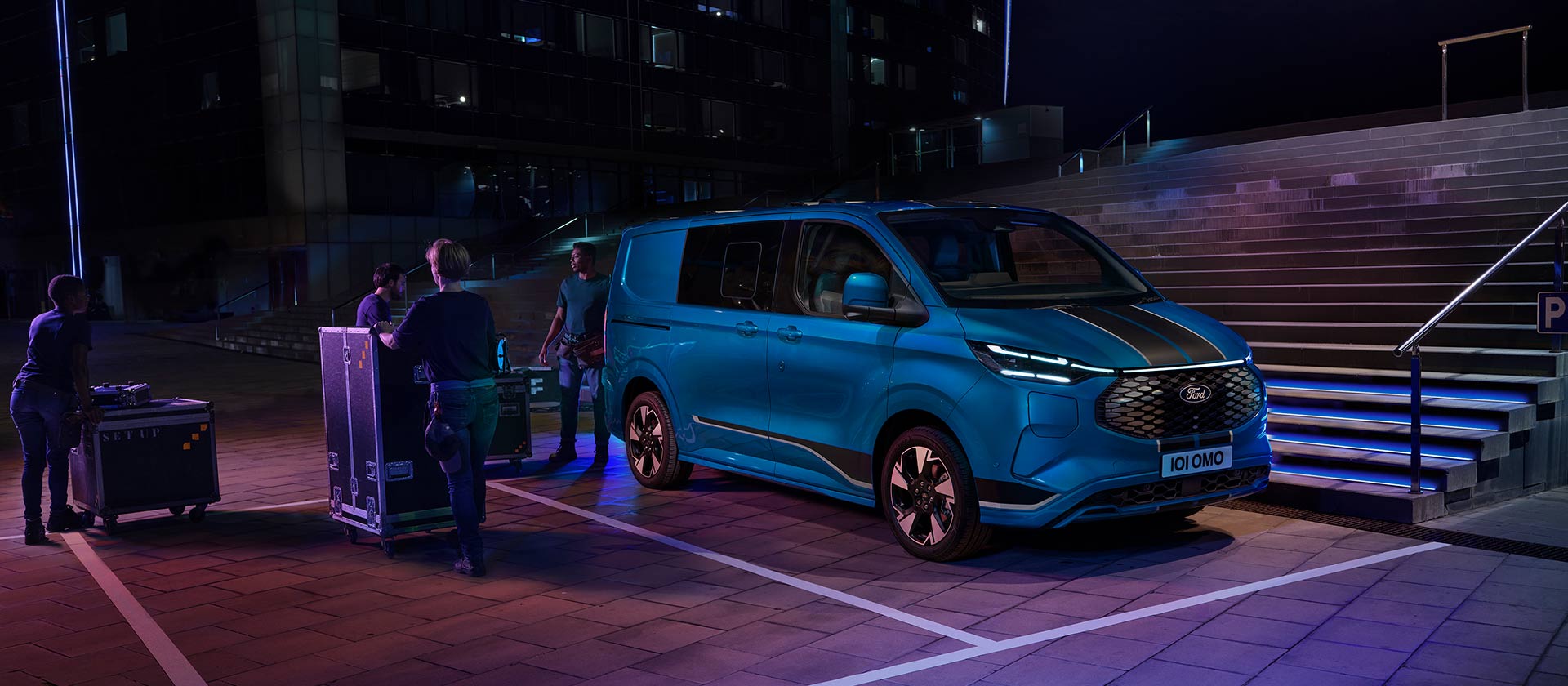 Μπλε ηλεκτρικό van Ford E-Transit Custom που φορτώνεται τη νύχτα. 