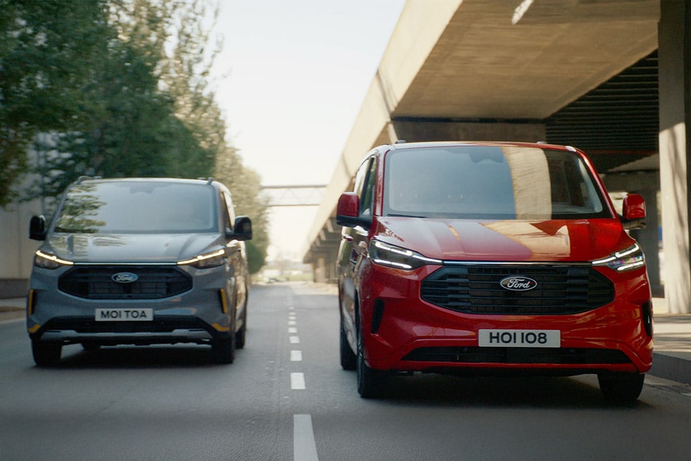 Γκρι και κόκκινο Ford Transit Custom van που κινείται σε αυτοκινητόδρομο.