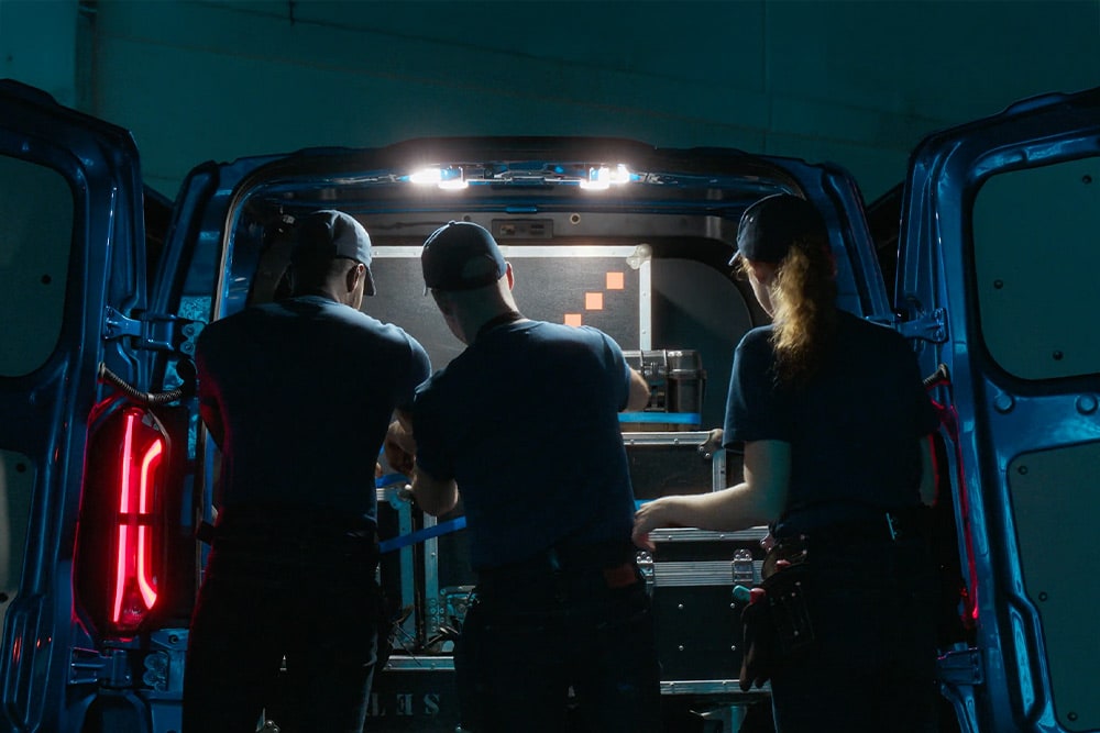 Τρία άτομα εργάζονται στο πίσω μέρος ενός Ford Transit Custom.