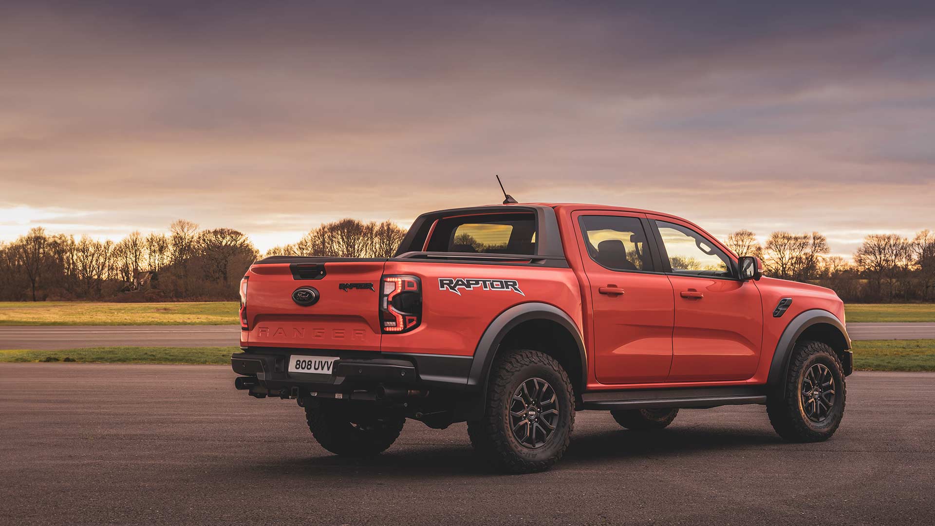 Πίσω όψη ενός Ford Ranger Raptor σε Code Orange καθώς κινείται σε πίστα.