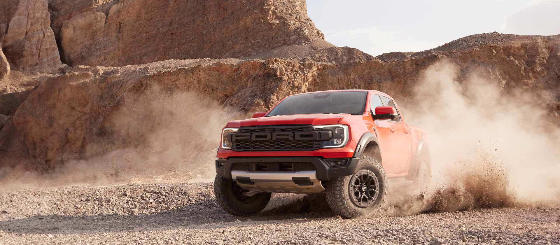 Ένα Ford Ranger Raptor σε Code Orange κινείται μέσα από θραύσματα βράχων.