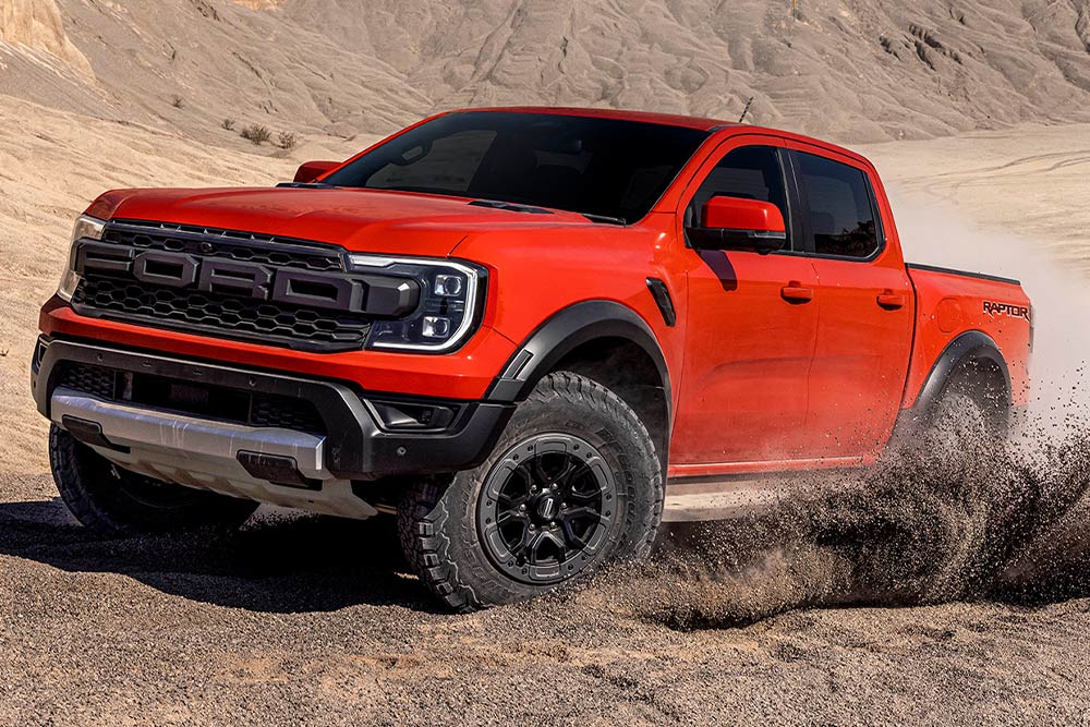 Ένα Ford Ranger Raptor σε Code Orange κινείται σε χώμα.
