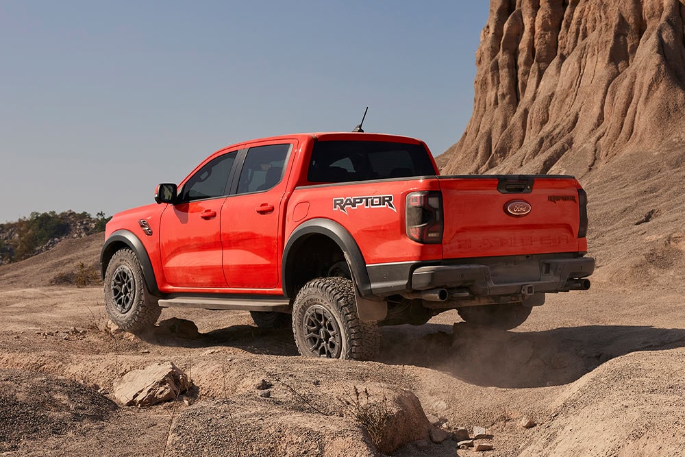 Ένα Ford Ranger Raptor σε Code Orange κινείται εκτός δρόμου σε ανηφόρα με πέτρες.