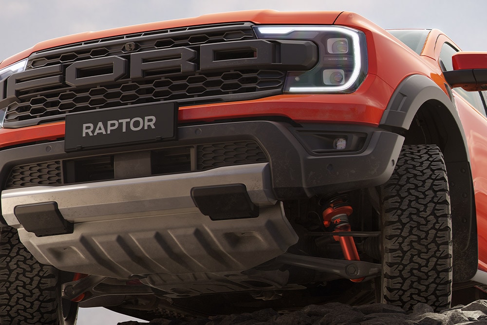 Μπροστινή κάτω πλευρά ενός Ford Ranger Raptor σε Code Orange όπου φαίνεται η ανάρτηση και μπροστινή μάσκα. 