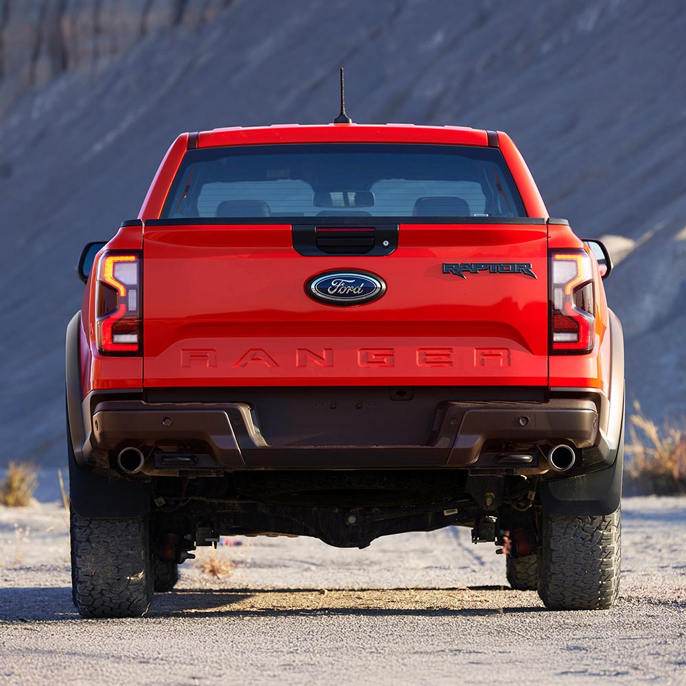 Οπίσθια όψη ενός Ford Ranger Raptor σε Code Orange σταθμευμένο σε εξωτερικό χώρο.