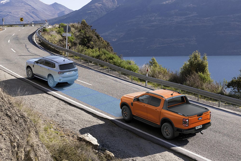 Κίτρινο Ford Ranger Raptor κινείται σε μια γραφική ορεινή διαδρομή, με έμφαση στα συστήματα υποβοήθησης οδηγού του οχήματος.