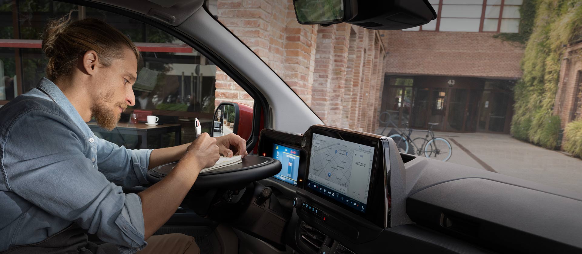 Άτομο που γράφει σε ένα σημειωματάριο μέσα σε ένα Ford Transit Custom.