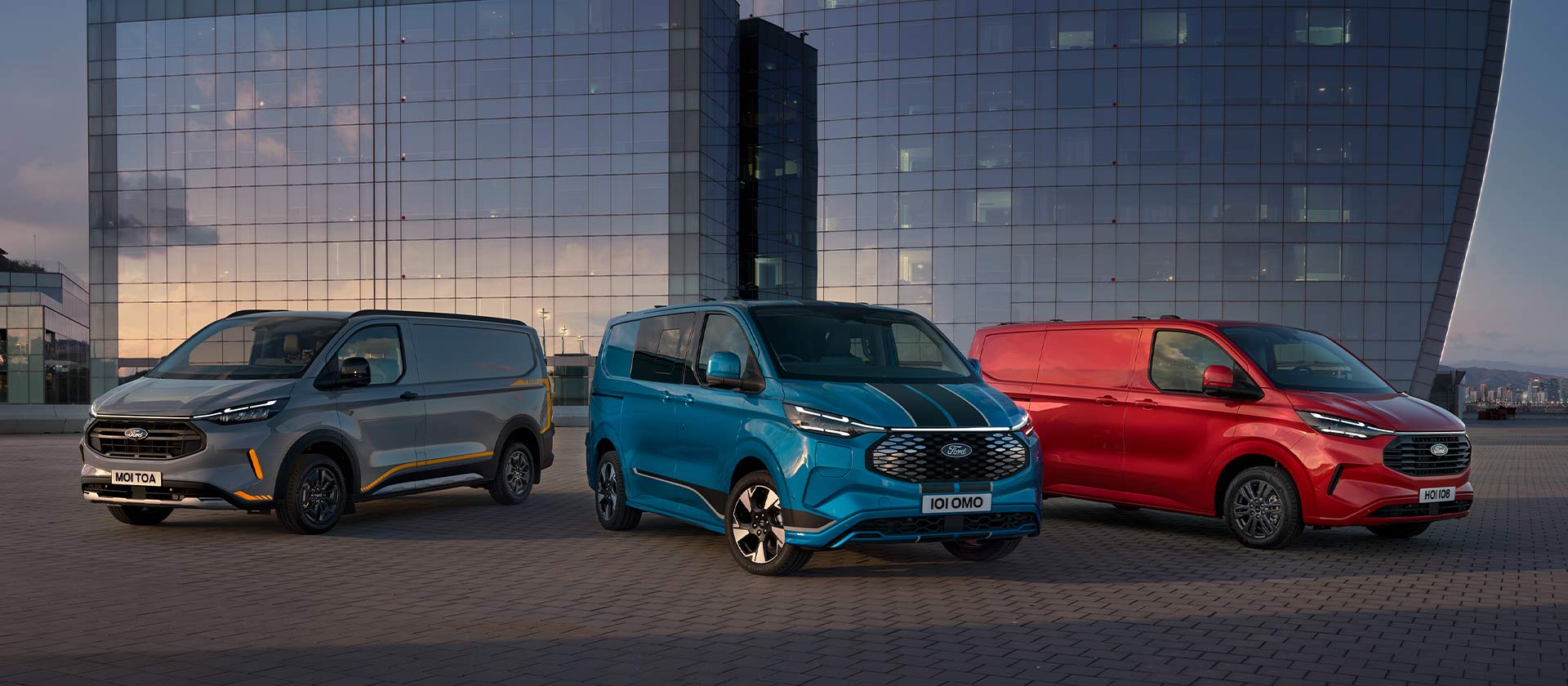 Τρία σταθμευμένα Ford Transit Custom Sport van σε γκρι, μπλε και κόκκινο χρώμα. 