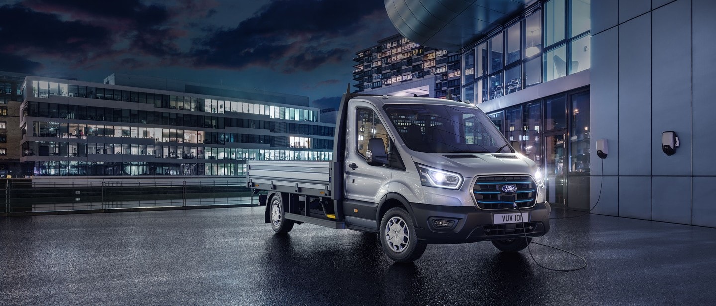 Νέo E-Transit Chassis πλευρική όψη με φόντο πόλη τη νύχτα και μπλε ηλεκτρικά φώτα.