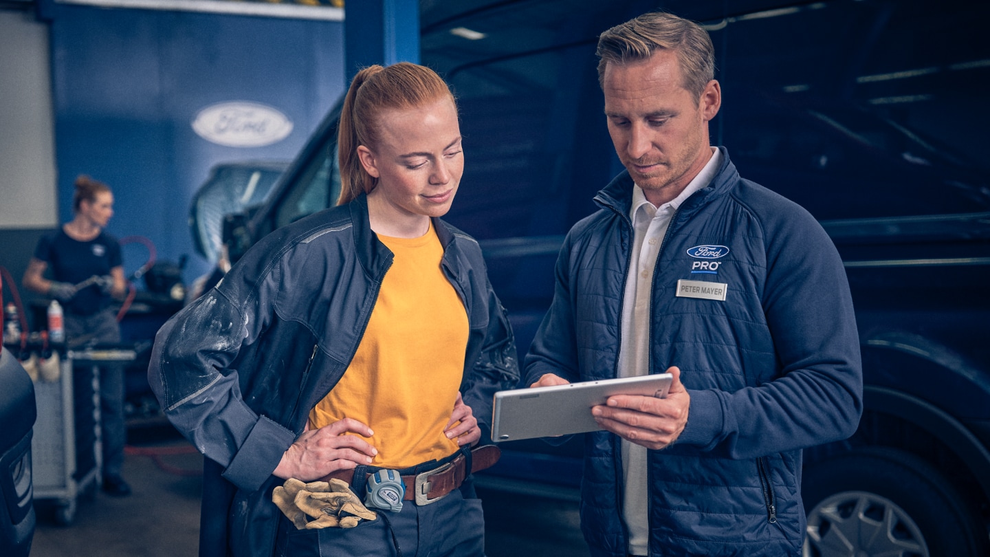 Υπάλληλος service και ιδιοκτήτης Ford E-Transit συζητούν χαρτιά.