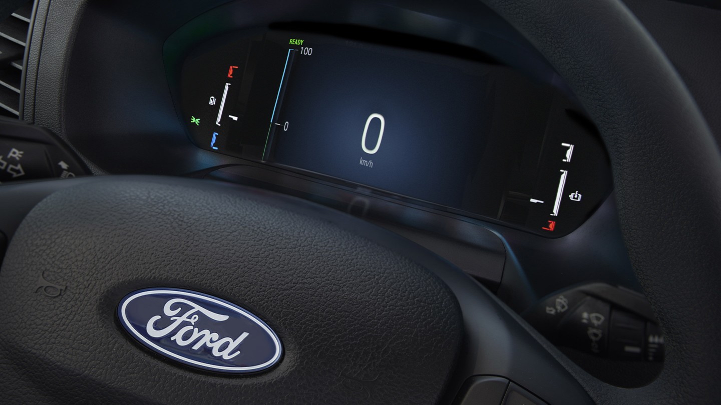 Κοντινή λήψη της οθόνης του ταμπλό του Ford E-Transit Chassis πίσω από το τιμόνι.