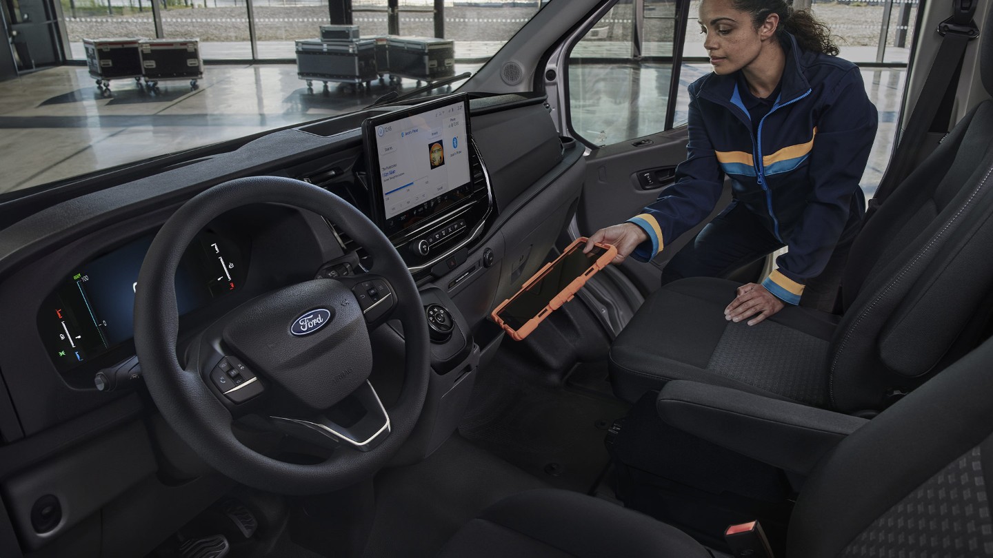 Λεπτομέρεια στο μπροστινό εσωτερικό του Ford E-Transit Chassis με γυναίκα τεχνικό που κρατά tablet.