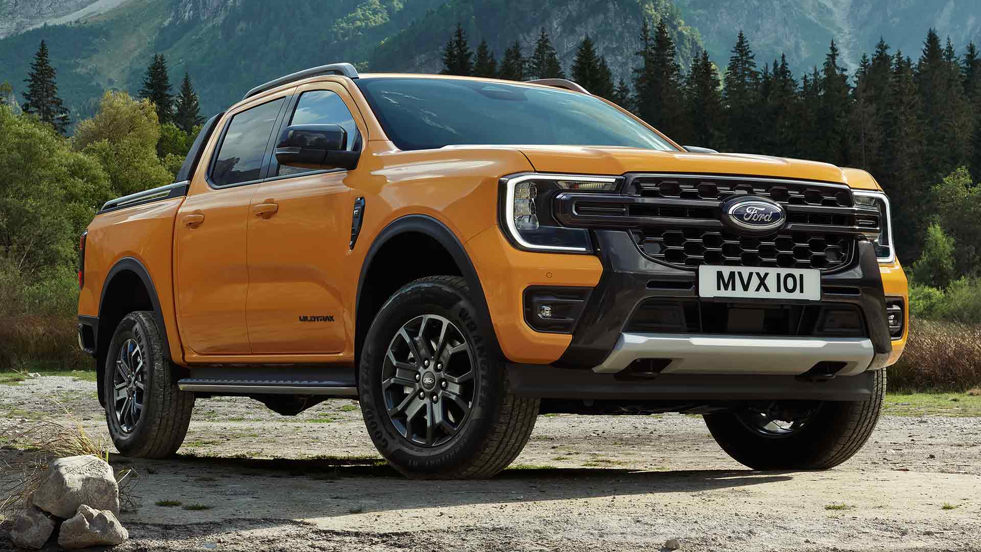 Κίτρινο Ford Ranger Double Cab Wildtrak με φόντο ένα γραφικό δάσος και βουνό.