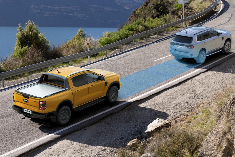  Ένα κίτρινο Ford Ranger χρησιμοποιεί το προηγμένο σύστημα υποβοήθησης οδηγού κατά μήκος ενός παράκτιου αυτοκινητόδρομου.