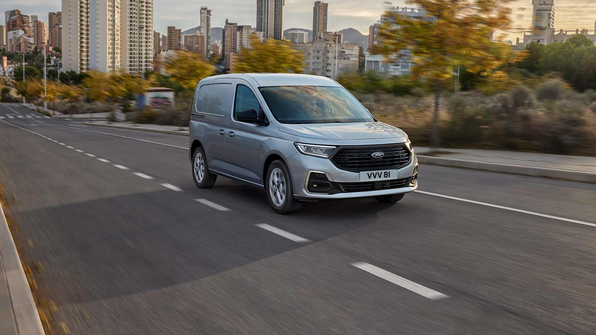 Ένα Ford Transit Connect καθώς κινείται σε μια πόλη, στο οποίο εμφανίζεται ο περιβάλλων φωτισμός ομίχλης με λεπτομέρειες χρωμίου και οι αυτόματοι προβολείς.