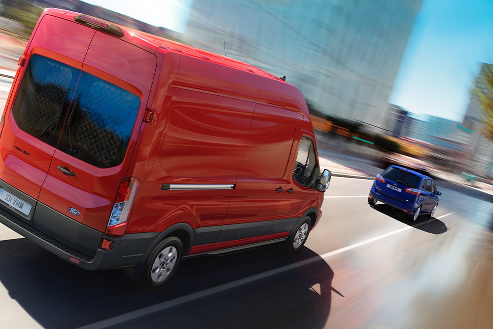 Κόκκινο Ford Transit van που κινείται σε έναν δρόμο.