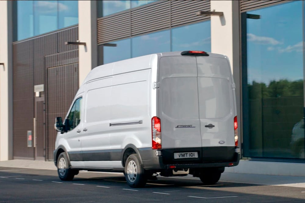 Πίσω μέρος ενός ασημί Ford Transit Van το οποίο είναι σταθμευμένο σε έναν δρόμο πόλης. 