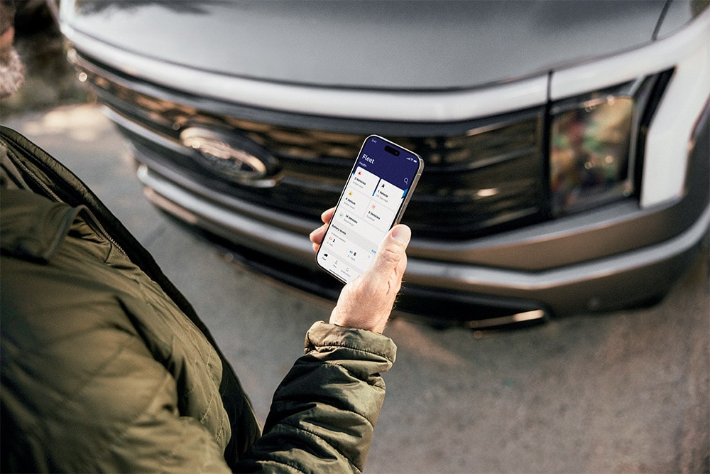 Άνδρας που κοιτάζει το smartphone του μπροστά από ένα Ford Ranger.