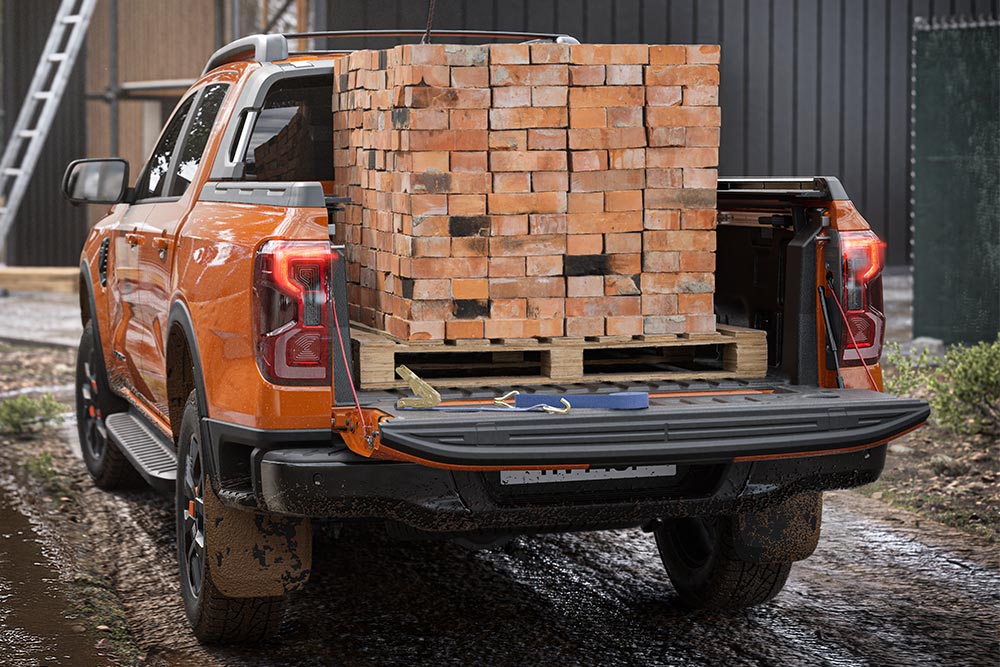 Άποψη του πίσω μέρους ενός πορτοκαλί Ford Ranger, με μια στοίβα τούβλα φορτωμένη στην καρότσα.